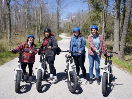 a group of people riding to cave point county park on electric bikes on a windy road in door county