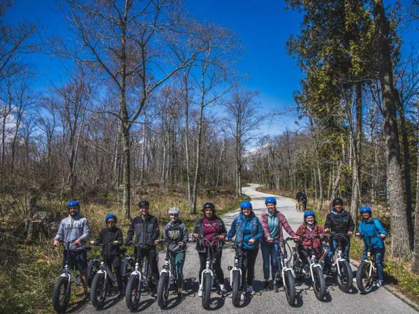 a group of people standing on a curvy road on the way to cave point county park in door county wisconsin