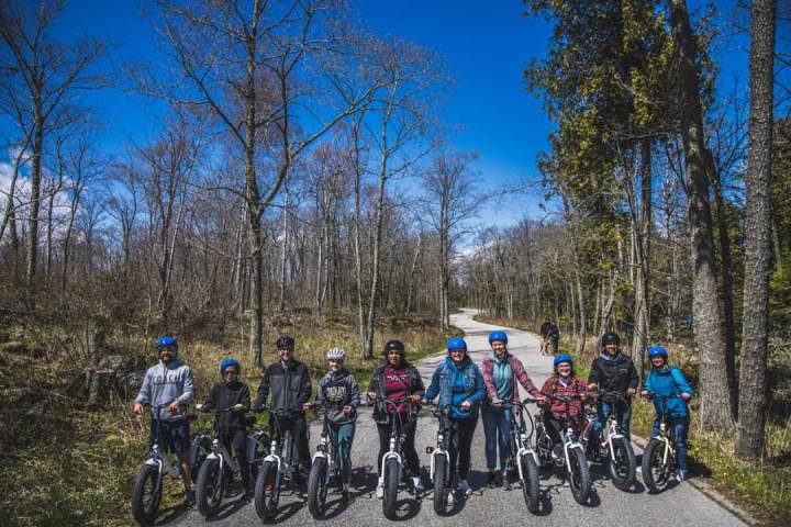 a group of people standing on a curvy road on the way to cave point county park in door county wisconsin