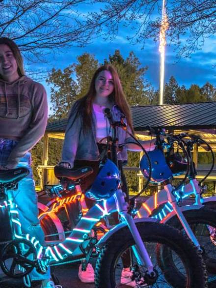 2 girls standing near e-bikes